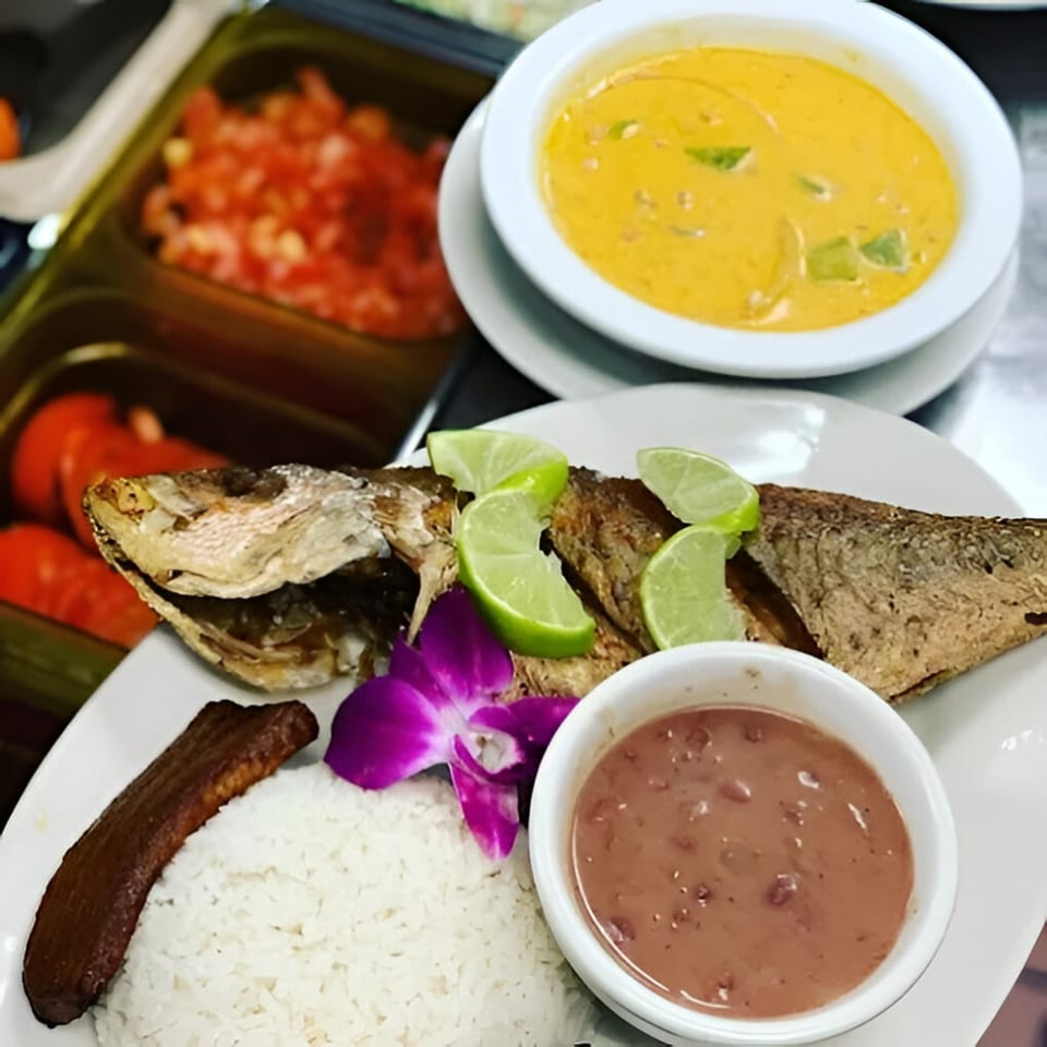 Belizean fried fish with lime, rice, plantain, beans, and a side of yellow soup.